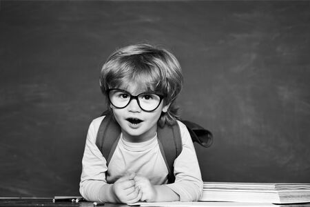 Education. Kids gets ready for school. Learning concept. First school day. Happy smiling pupils drawing at the desk. School kids against green chalkboard.の写真素材
