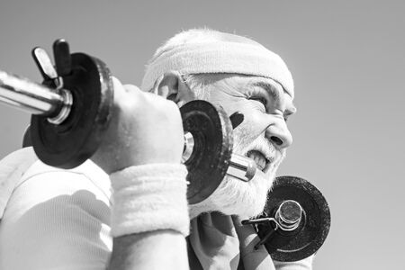Health club or rehabilitation center for elderly aged pensioner. Senior sport man lifting dumbbells...