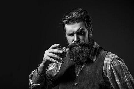 Man Bartender holding glass of whisky. Man or businessman drinks whiskey on black background....