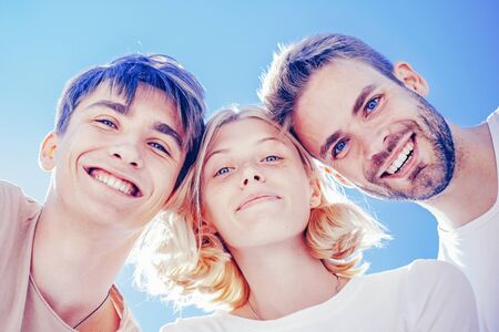 Group of people smiling and huddle together. Friendship relations. Handsome males. Friendship day. Trust relations and liking. Blonde happy girl with two handsome boys.の写真素材