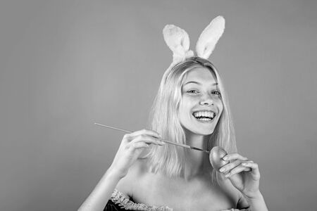 Beautiful sensual blonde. Happy young woman painting eggs on a green background. Blonde Girl wearing bunny ears and having Easter Eggs. Bunny rabbit.の写真素材