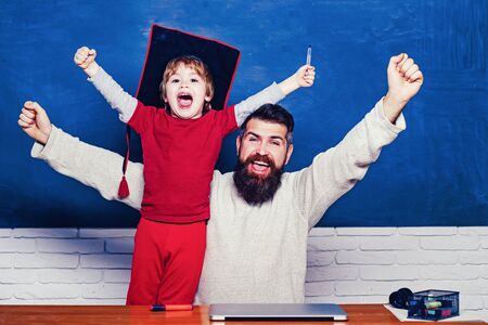 Hooray. Daddy and son raising clenched fists in hooray gesture. Father teaching her son in classroom...