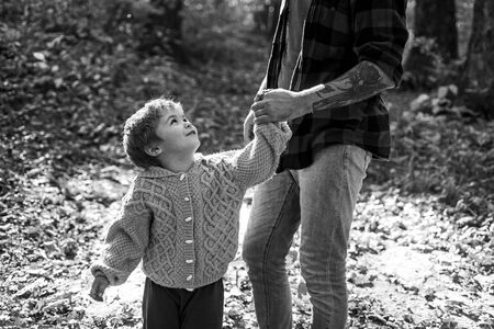 Happy kids autumn. We like autumn time together. Parent teach baby. Happy family, father and baby son playing and laughing. Little boy with his father outdoors.の写真素材