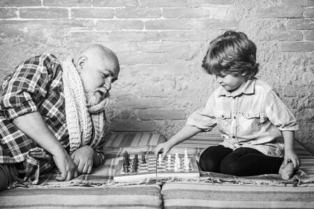 Senior man teaching his grandson to play chess. Handsome grandpa and grandson are playing chess...