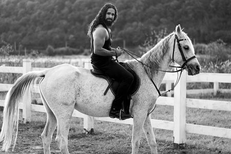 Sexy man on horse. Young jockey training his horse for a ride. Good looking, hunky cowboy rides...