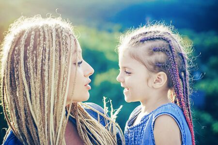 Mother and child girl playing and hugging. Braiding hair. Nice child girl with plaits. Hair in trendy weave plait.の写真素材