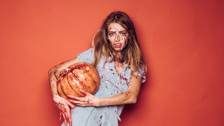 Girl with pumpkin. Zombie. Face of Halloween woman on red background isolated.の写真素材
