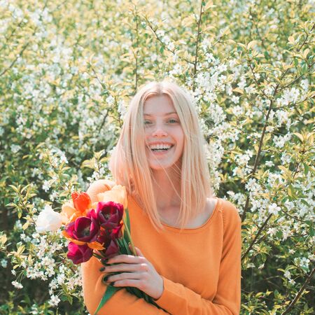 8 march. Happy woman relaxing in the tulip fields. Womens day, 8 march. Field of colorful bright red tulips.の写真素材