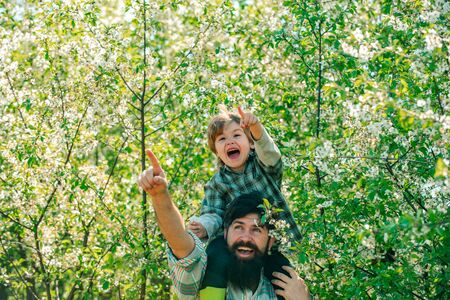 Fathers day. Father and son on spring blossom garden background. Beautiful young smiling family having fun at farm yard. I love our moments in the countryside.の写真素材