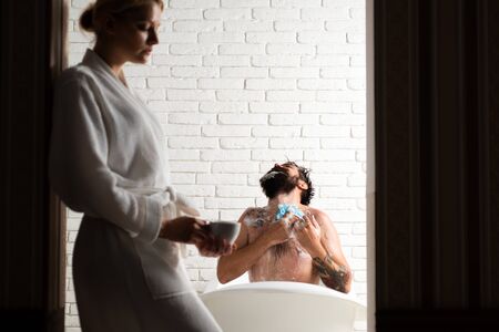 Happy young couple in bathroom at home. Couple of sensual girl and naked man trimming beard. Young...