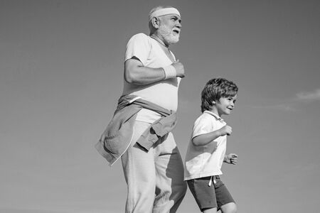 Jog and run marathon for family. The old and young sportsmen running on the road. Portrait of healthy senior sport man and sporty little boy jogging. Summer and active holidays.の写真素材