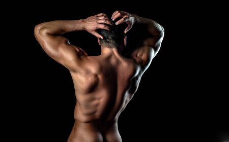 Young mans naked ass and back on black isolated background. Metrosexual concept. Shirtless athletic man turned back on black background.の写真素材