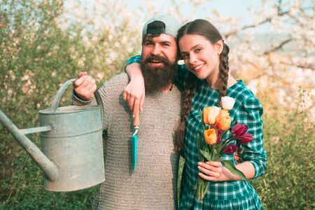 A group of friends enjoy the spring nature and take care of the plants. Funny gardener couple holding garden tools at spring nature background.の写真素材