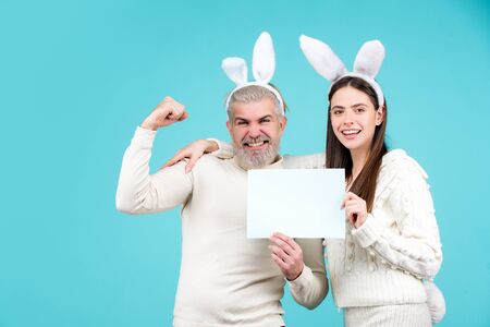 Easter couple dressed in costume holding blank white board for your text. Easter bunny couple on...