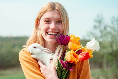 Easter Bunny. Beautiful young woman with bunny rabbit on farm.の写真素材