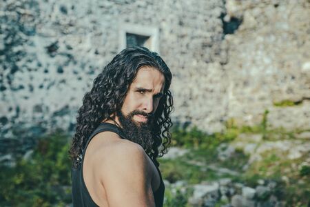 Bearded attractive man at ancient architecture wall background. Close up portrait of handsome middle-aged man with unusual appearance looking at camera. Man lifestyle concept.の写真素材