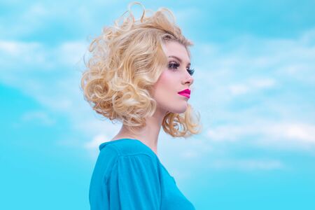 Close-up portrait of sexy caucasian young woman with beautiful blue eyes. On sky background.の写真素材