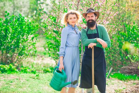 A farmer and his wife standing in their field. Crop planting at fields. Farmars couple enjoy spring nature and take care about her plants.の写真素材