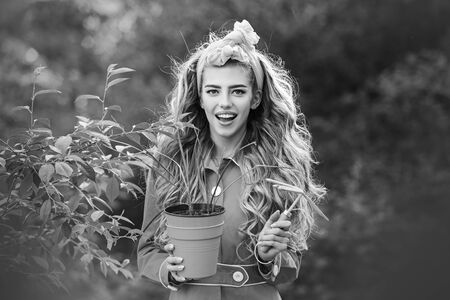 Garden woman with tools. Planting and flower growing concept. Beautiful girl in spring garden. Beautiful girl holding a flower pot.の写真素材