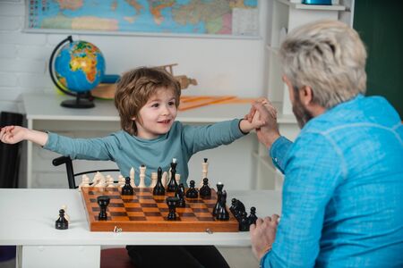 At home. Dad with his child son are playing Chess. Chess strategy. Back to school and Education concept.の写真素材