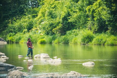 Angler catching the fish. Hobby of real man. Gone fishing. Happy fly fishing. Fisher fishing...