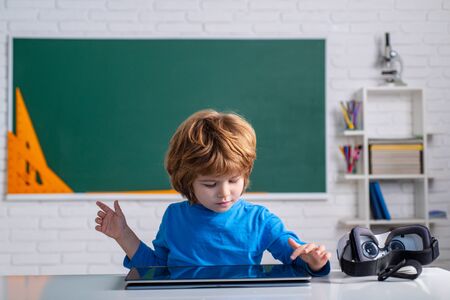 Pupil with digital tablet in school classroom. Little boy playing with digital tablet.の写真素材