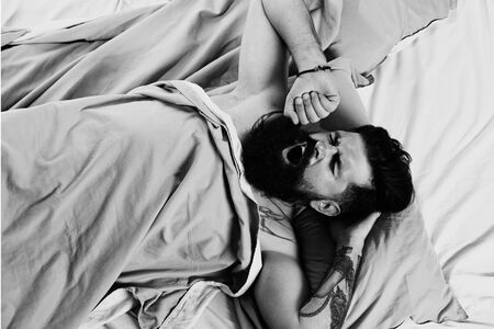 Man is lying on bed and enjoying the morning. Man having problems with sleep. Bearded man wake up on...