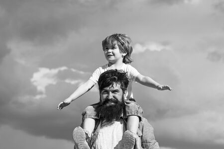 Concept of Fathers day. Father and son together. Cute boy with dad playing outdoor. Enjoy. Childhood. Father giving son ride on back in park. Generation.の写真素材