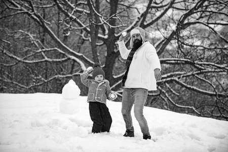 Father and son play with snowball on winter white background. Christmas holidays and winter new year with father and son.の写真素材
