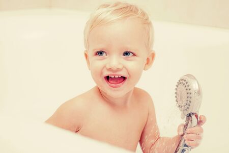 Child bubble bath. Pretty smiling little boy taking a bath with soap suds. Cute little boy washing....
