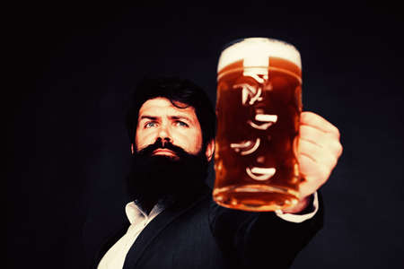 Handsome bearded man drinking beer. Portrait of handsome young man tasting a draft beer. Man holding mug of beer. Man holds glass of beer.の写真素材