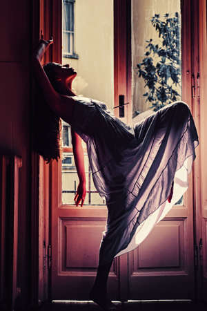 Woman meets morning near balcony. Relax time. Young woman standing near window.の写真素材