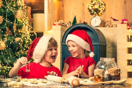 Funny kids are preparing the dough playing with flour in the kitchen. Funny Kids in kitchen making christmas cookies.の写真素材