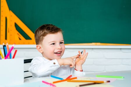 Happy smiling boy going to school for the first time. Cheerful smiling little boy having fun against blackboard. Back to School.の写真素材