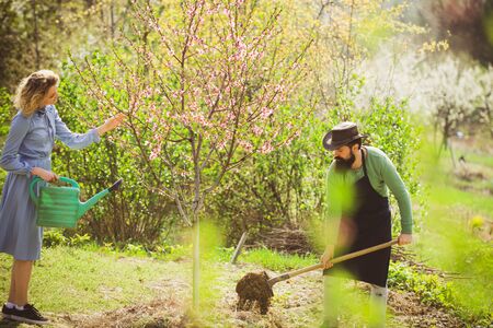 Portrait of a young happy couple in yard during spring season. Happy Couple Farmers working with spud on spring fieldの写真素材