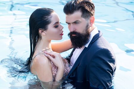 Couple in dress having Party in swimming pool. Celebrity couple, fashionable pair of elegant people. Romantic couple in love standing in swimming pool.の写真素材