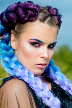 Pensive woman posing outdoor. Serious lady with braids and fashiom make up. Two thick braids of...