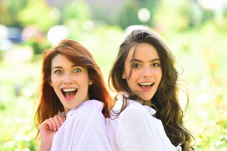 Two excited women friends girls posing on green nature background. People lifestyle concept.の写真素材