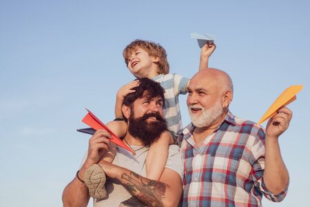 Grandfather with son and grandson having fun in park. Fathers day concept. Cute child hugging his father and grandfather. Child happy. Grandfather playtime.の写真素材
