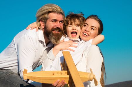 Happy family hug embrace outdoors. Cheerful family having fun outdoors. Child playing with mother and father and having fun. Son hugging parents on sky nature.の写真素材