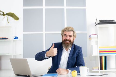Happy manager in office thumb up. Caucasian businessman show thumb up in his office.の写真素材