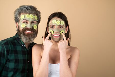 Funny friends with facial masks over isolated background. Funny couple has fun with a facial mask with Cucumber and aloe vera having fun.の写真素材