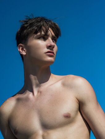 Handsome shirtless young man on lue sky background.の写真素材