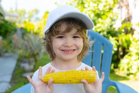 Happy Little boy eating corn on the cob. Food for kids.