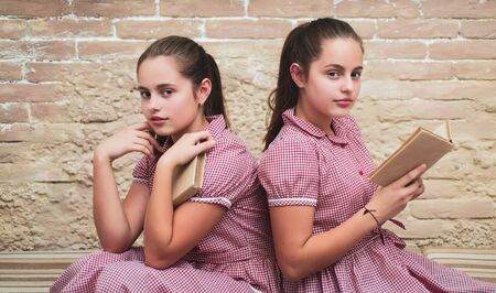 Vintage literature. Traditional education. Outdated approach. Literature lesson. Adorable students study literature together. Homeschooling concept. Sisters girls vintage dresses reading booksの写真素材