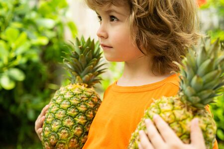 Child with pineapple in garden. Kids in tropical resort. Family summer vacation on exotic island. Fruit for children.の写真素材