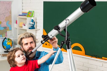 Pupil watching stars with a teacher. Astronomy telescope. Happy cute industrious child is sitting at...