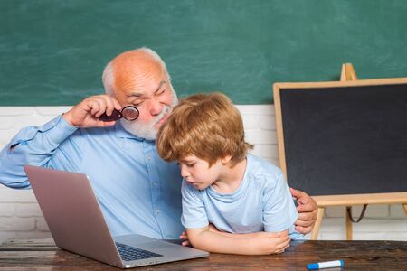 Back to school and Education concept. Pupil preparing for test or exam. Grandfather with grandson learning lesson together. Teacher helping young boy with lesson.の写真素材