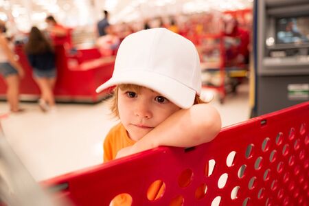 Funny kids shopping. Joyful beautiful child boy in supermarket buys vegetables. Healthy food for children.の写真素材