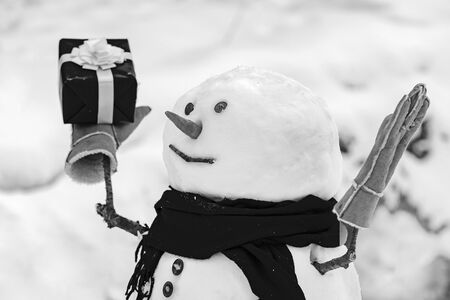Snowman with shopping bag and gift on the white snow background. Greeting snowman. Merry Christmas and happy new year greeting card with copy-spaceの写真素材